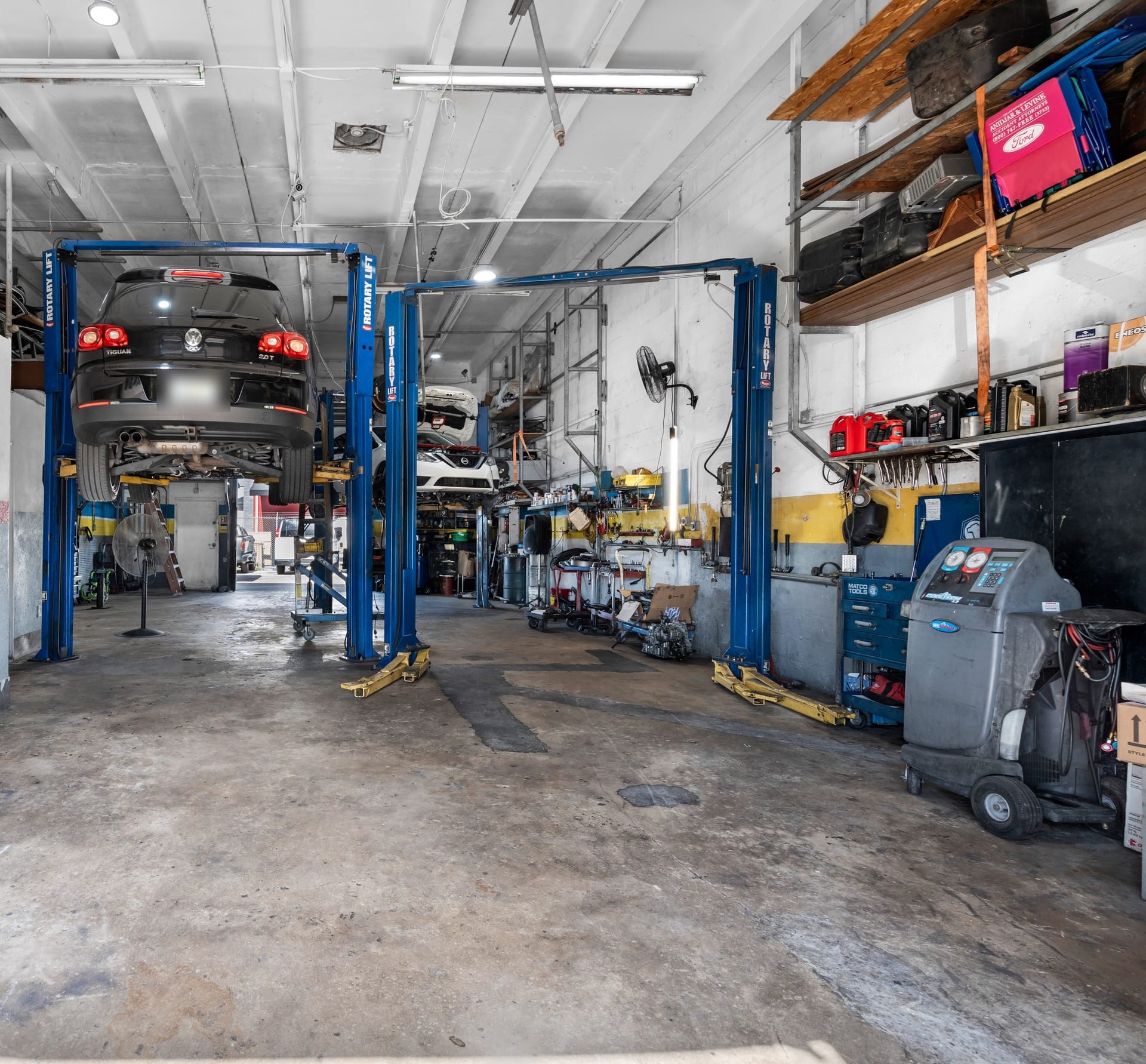 A/C service machine beside a car on a lift at Wires Auto Repair, Miami