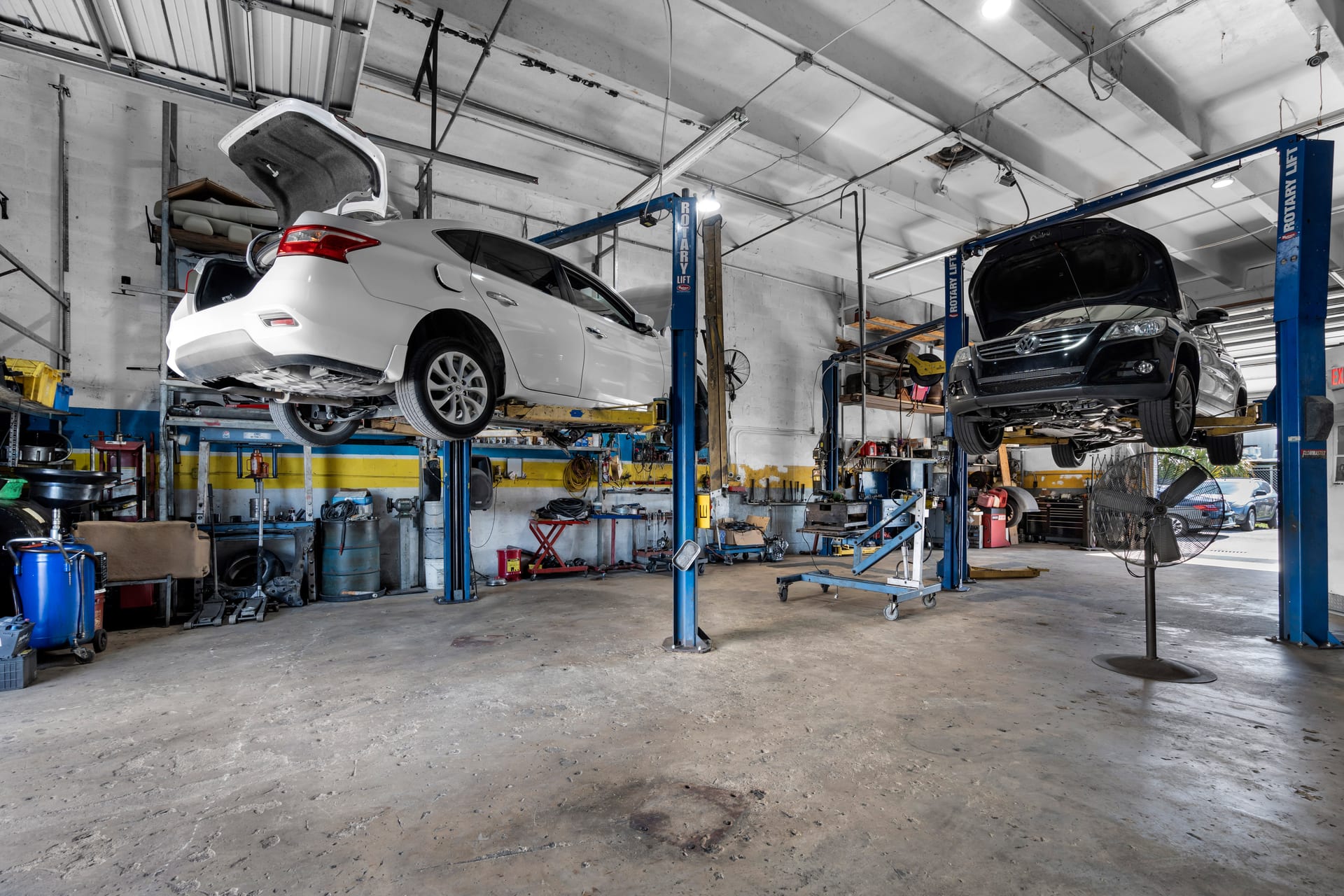 Two cars raised on lifts in the Wires Auto Repair service bay, Miami