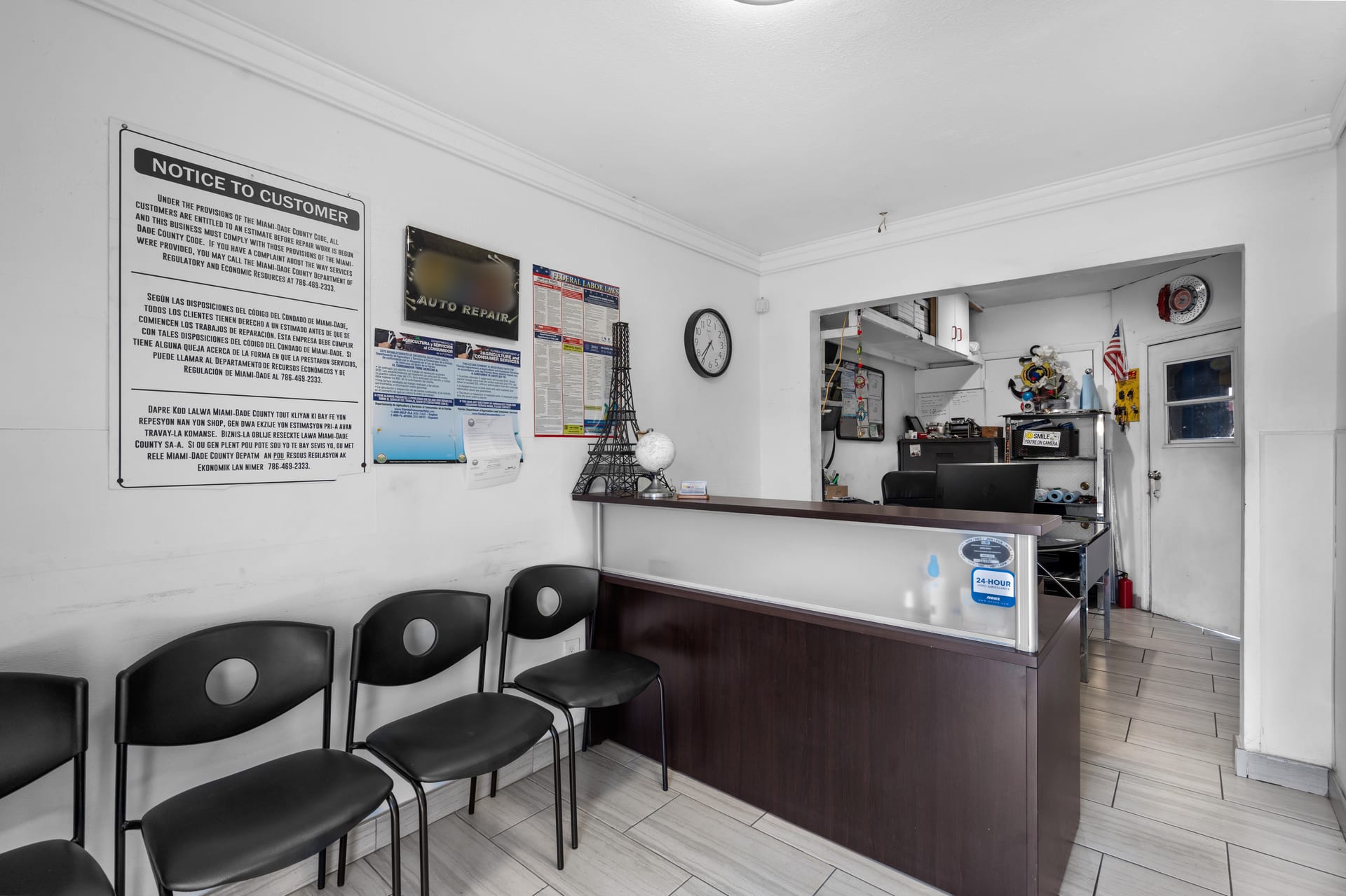 The shop's front office with waiting chairs and the Miami-Dade County estimate notice on the wall